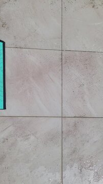 Floor squeegee cleaning tiled floor with water
