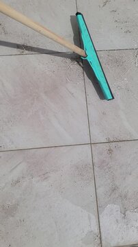 Floor squeegee cleaning sand from tiled floor