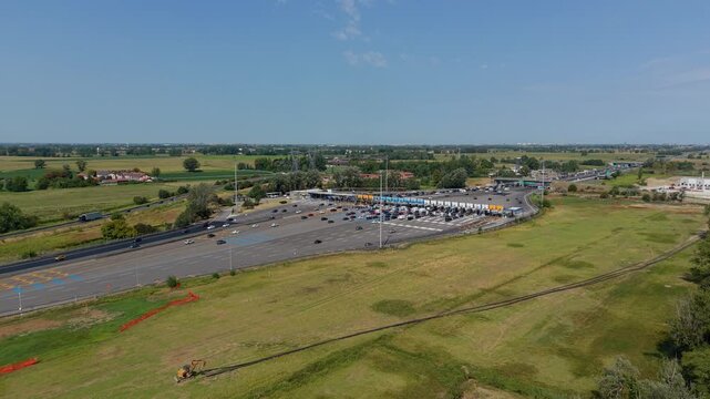 Aerial view of Autostrada A1 toll plaza near Melegnano, Italy, showing motorway infrastructure, vehicle flow and transportation systems for commercial use.