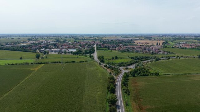 Aerial View of Country Road: An expansive aerial perspective showcases a winding country road cutting through vibrant green fields, Tavazzano con Villavesco, Lodi, Italy