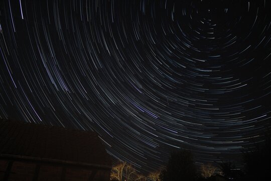 Sternspuren (Startrails) am Nachthimmel &uuml;ber der dunklen Landschaft