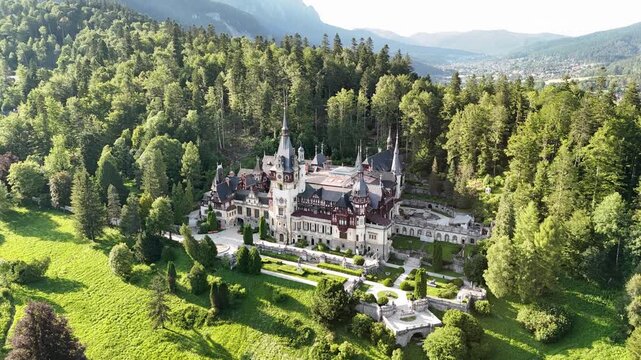 Aerial hyperlapse showcasing Peles Castle nestled within lush forest in Sinaia, Romania. Cinematic drone view highlighting the iconic Neo-Renaissance palace and its picturesque mountain setting
