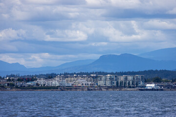 Fototapeta premium Sidney Waterfront Town on Vancouver Island With Mountains, Harbour Buildings and Dramatic Cloudy Sky