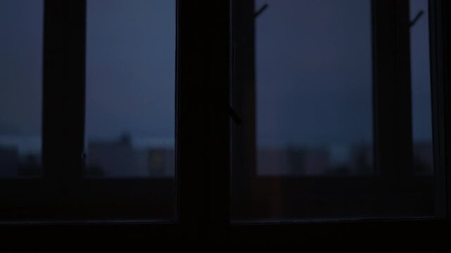 Emergency light: Dark window panes with soft blue dusk light and blurred vertical shadows in moody interior scene