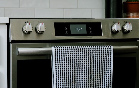 Man setting digital clock time on kitchen microwave stove appliances, representing changing clocks - daylight savings time, spring forward, fall back
