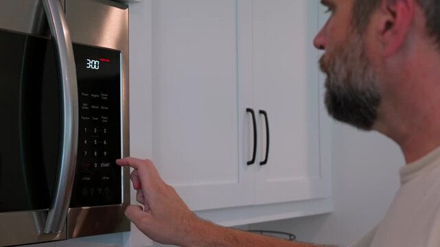 Man setting digital clock time on kitchen microwave stove appliances, representing changing clocks - daylight savings time, spring forward, fall back