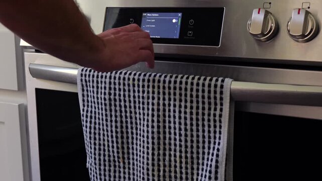 Man setting digital clock time on kitchen microwave stove appliances, representing changing clocks - daylight savings time, spring forward, fall back