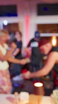 Blurred partygoer dancing in colorful nightlife scene with vibrant lights and lively crowd