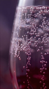 Close up of fizzy red soda bubbles rising in a glass with dark background