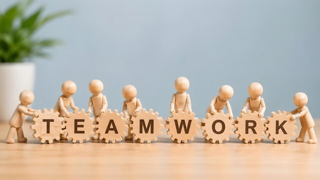 Business teamwork and collaboration concept. Wooden mannequin figures working together holding up gears spelling the word teamwork.