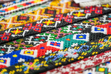Obraz premium Vibrant beadwork pattern in bright primary and secondary colors, showcasing intricate artisanal design, detailed craftsmanship, colorful repetitive symmetrical arrangement