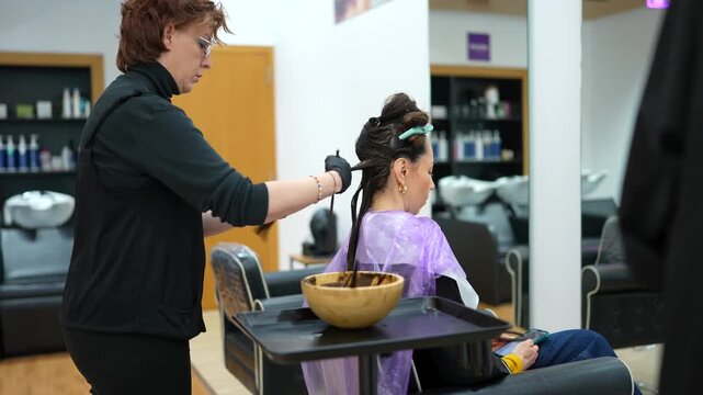 Professional hairdresser applying hair dye to a client's hair