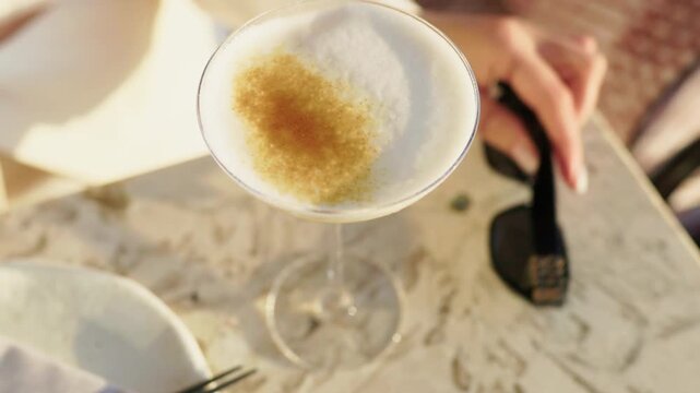 Elegant cocktail in coupe glass with frothy top and spice garnish on softly lit dinner table