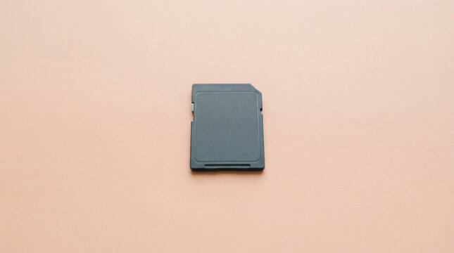 Black memory card on a textured peach background, representing digital storage and data, suitable for technology concepts and design element.