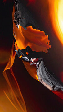 Dramatic abstract closeup of burning paper with glowing orange embers and charred black edges, evoking destructive beauty with nobody present. Great for creative backdrops.