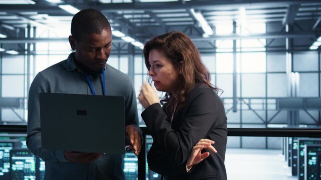 Server room staff handle IT team with laptop, combining laptop workflow, notebook device and technical coordination within a controlled technical environment.