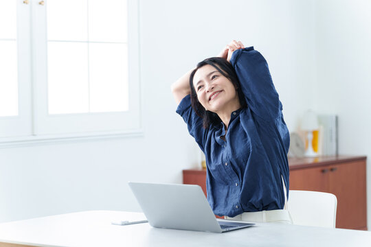 デスクワーク中にストレッチをする中高年女性