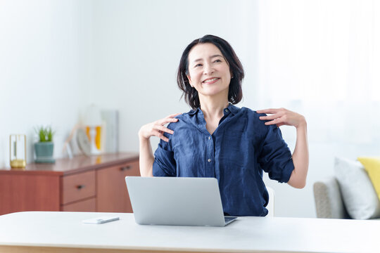 デスクワーク中にストレッチをする中高年女性