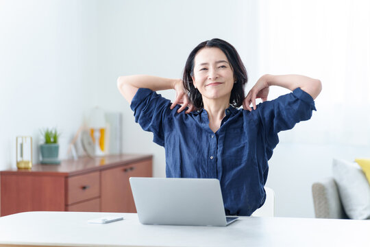 デスクワーク中にストレッチをする中高年女性