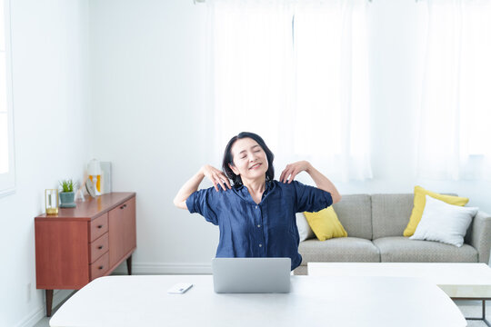 デスクワーク中にストレッチをする中高年女性