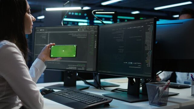 Engineer monitors cybersecurity risks inside a server hub with a chroma key smartphone, connecting network security and data protection with enterprise infrastructure work
