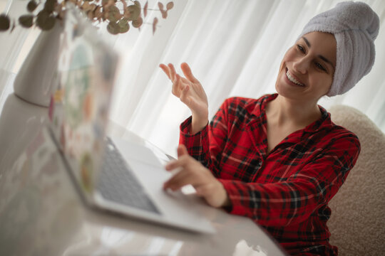 Woman waving during video call on laptop after shower