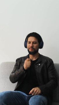 Vertical detailed view of a happy man listening music on a wireless headcase and doing some air drums