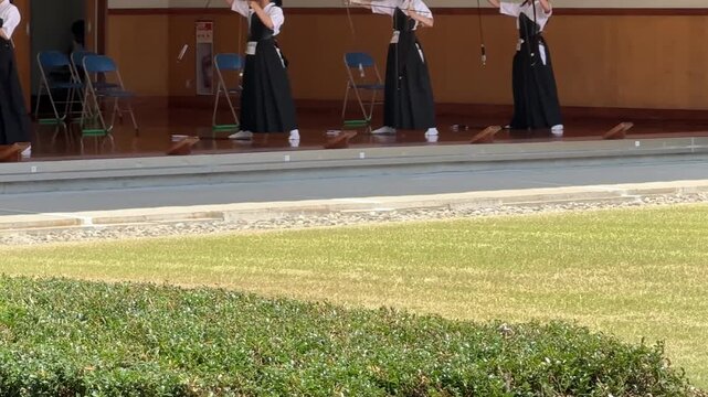 Kyudo archers raising bows overhead in traditional Japanese archery form at a tournament in Japan