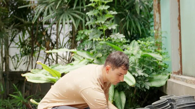 Male botanist caring and watering plants in greenhouse, botany research and plant biology study, sustainable agriculture, herbal cultivation, environmental science and natural medicine production
