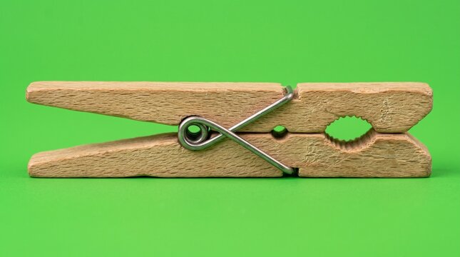 Wooden clothespin on green background. Natural laundry peg for hanging clothes or crafts.