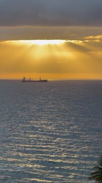 Vertical KD wide motion shot of dramatic cloudy sky over ocean at sunrise revealing a ship on horizon