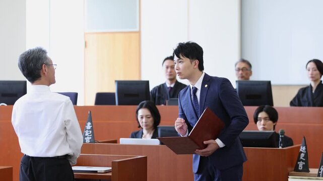 法廷で証人尋問を行う若手弁護士と証人の法廷シーン