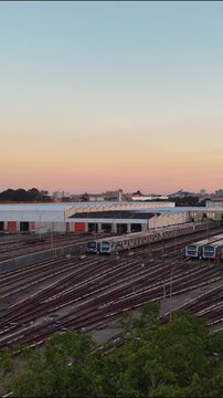 Vertical aerial view of commuter trains parked in a large railway depot at sunset
