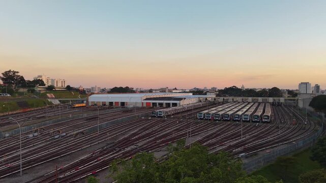 Aerial view of commuter trains parked in a large railway depot at sunset