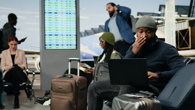 Black entrepreneur handles a crisis phone call in an airport lounge after receiving bad news about a startup mistake, appearing distraught in casual business clothing before departure.