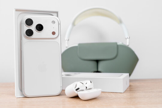 Bar, Montenegro: February 6, 2026: White apple iphone 17 pro in box with green airpods max in smart case and open wireless earbuds on wooden table, premium audio tech concept