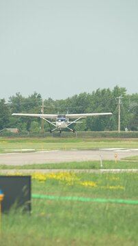 Small single engine Cessna 172 aircraft battles heavy crosswind while landing at rural airport runway surrounded by grass fields and trees