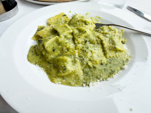 Close up a white plate filled with healthy organic Italian pesto ravioli
