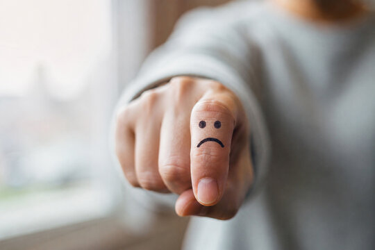 AI generated close up of pointing finger sad face symbol representing negative emotions mental health stress customer dissatisfaction feedback emotional wellbeing