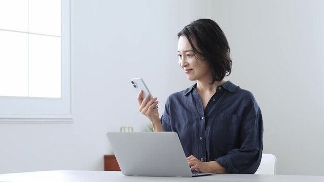 パソコンとスマートフォンを使う中高年女性