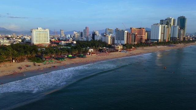 Smooth front-facing aerial drone footage flying along Da Nang beach during sunrise. Calm waves, tropical coastline and peaceful morning atmosphere make this clip ideal for travel, tourism, wellness an