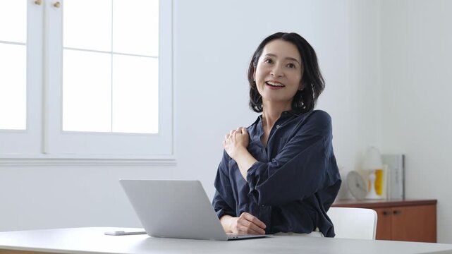 デスクワーク中にストレッチをする中高年女性