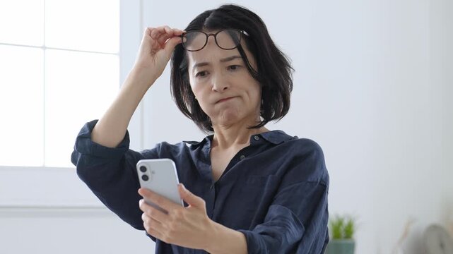 スマートフォンを使う老眼の中高年女性