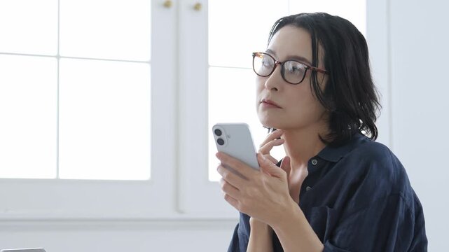 困った表情でスマートフォンを使う中高年女性