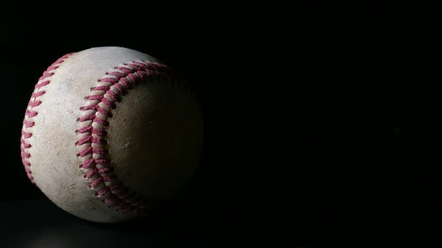A well worn baseball rotating isolated against a black background. Sports or game ball concept with copy space.