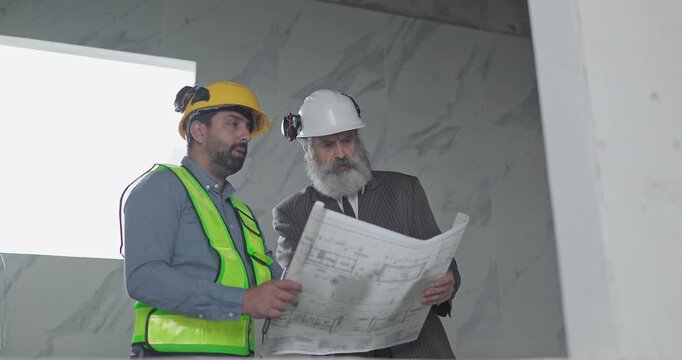 Engineer and businessman reviewing blueprint construction plans at house building site