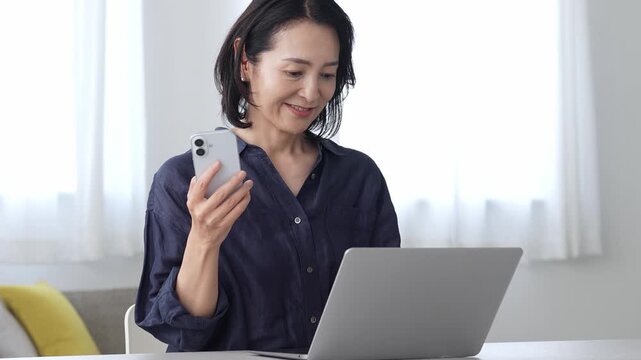 パソコンとスマートフォンを使う中高年女性