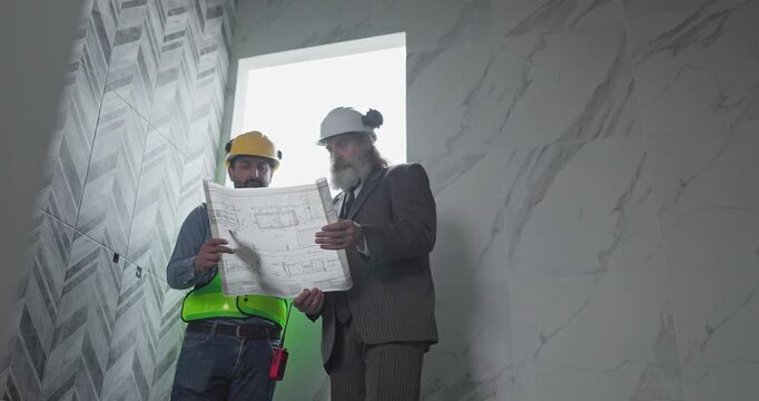 Engineer and businessman reviewing blueprint construction plans at house building site