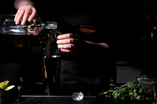 Liquor pouring into jigger over shaker on bar counter. Daiquiri, southside drink preparation with rum, gin or vodka.