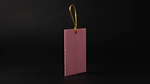 Pink paper tag spinning against a dark background in the studio